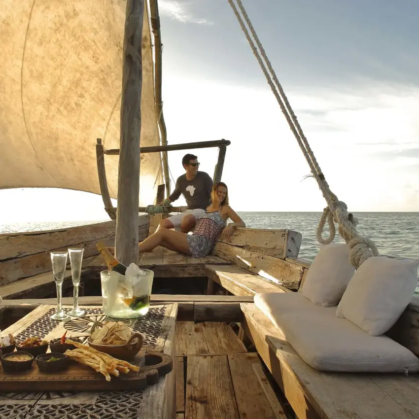 Guests sailing on traditional dhow boat at sea, Mnemba Island, Zanzibar & Pemba, Tanzania