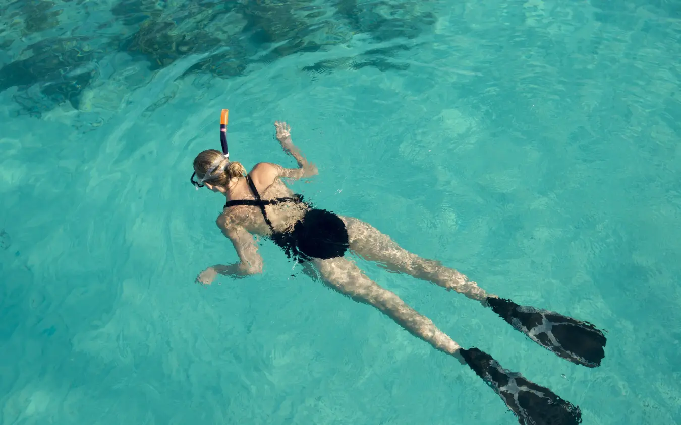 Snorkeler in turquoise water with fins and snorkel gear, Mnemba Island, Zanzibar & Pemba, Tanzania