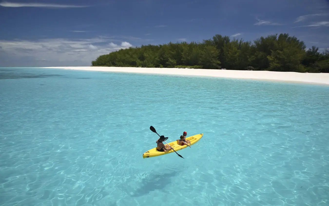 Guest kayaking in turquoise waters near white sand beach, Mnemba Island, Zanzibar & Pemba, Tanzania