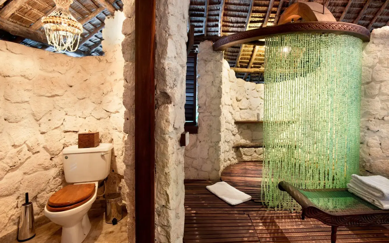 Rustic bathroom with stone walls and outdoor shower area, Mnemba Island, Zanzibar & Pemba, Tanzania