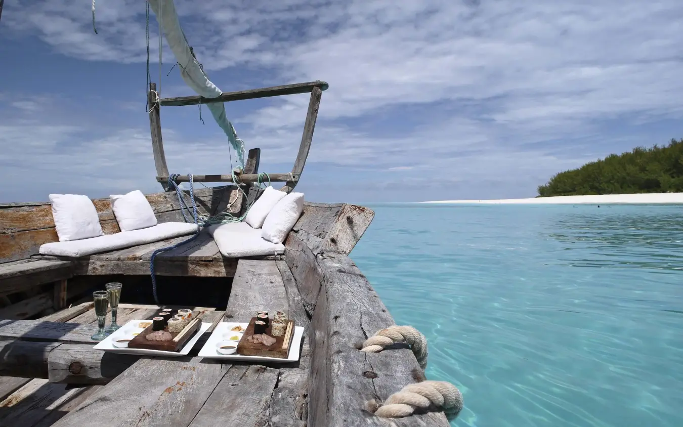 Traditional wooden dhow boat with cushioned seating overlooking turquoise waters, Mnemba Island, Zanzibar & Pemba, Tanzania