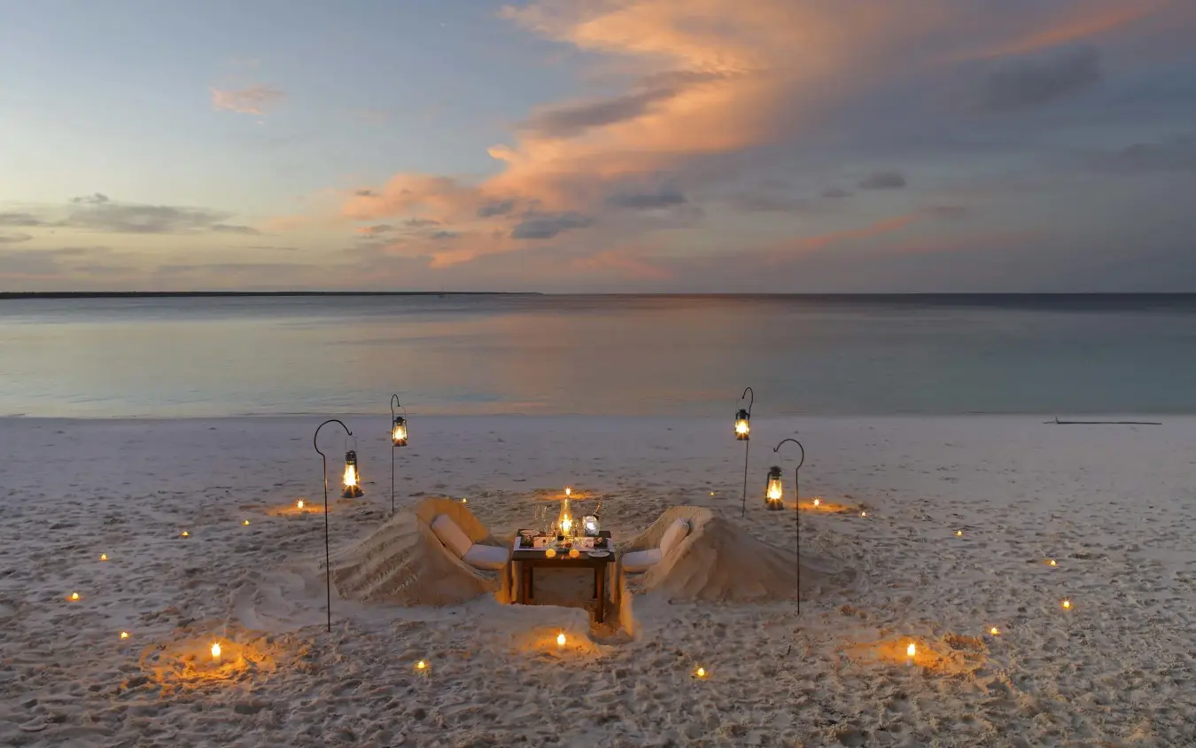 Beach dinner setup with lanterns at sunset over ocean, Mnemba Island, Zanzibar & Pemba, Tanzania