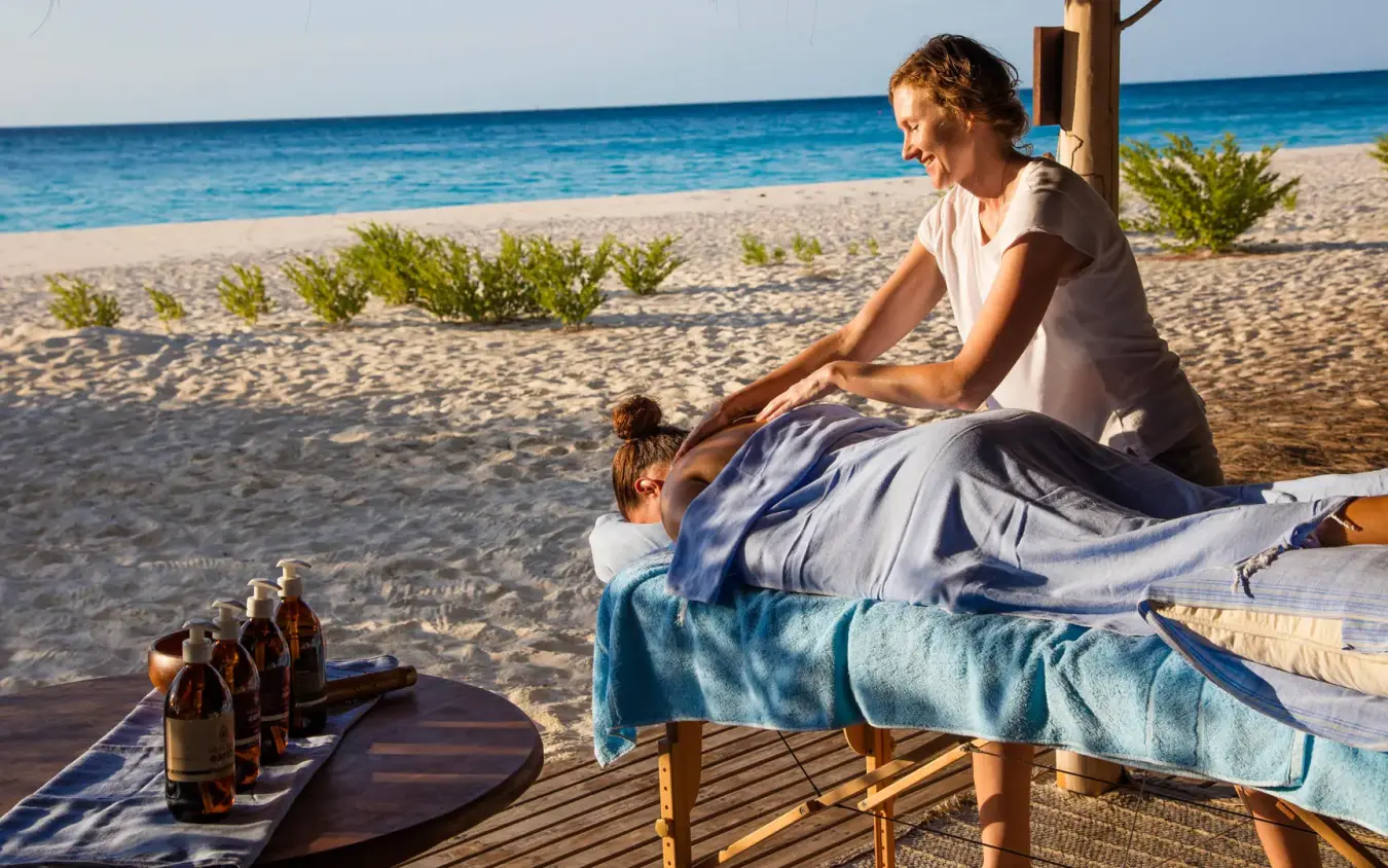 Woman and child relaxing on beachfront deck with ocean view, Mnemba Island, Zanzibar & Pemba, Tanzania