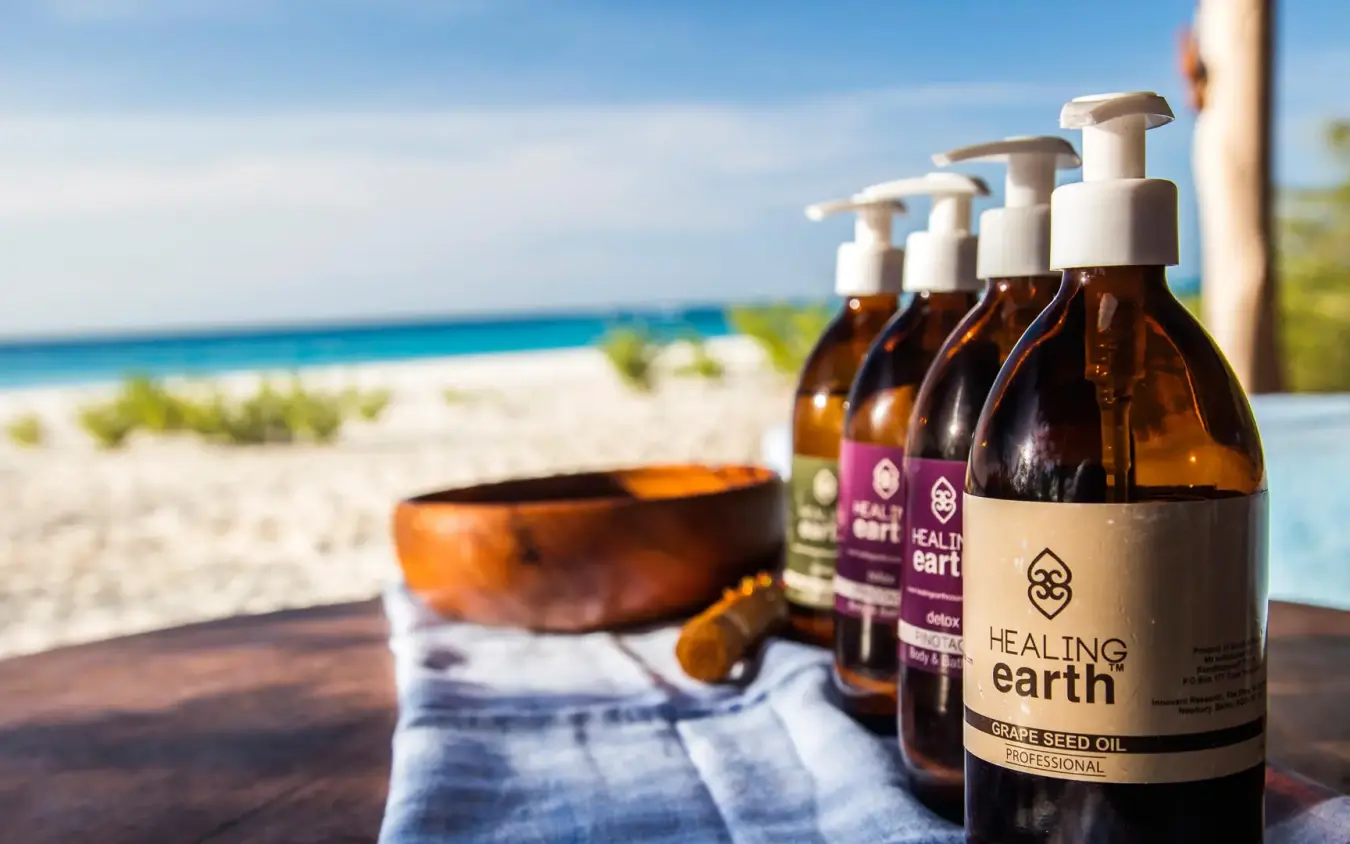 Skincare products displayed on wooden table overlooking beach, Mnemba Island, Zanzibar & Pemba, Tanzania