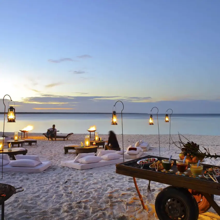 Beach dining setup at sunset with lanterns and fire pits, Mnemba Island, Zanzibar & Pemba, Tanzania