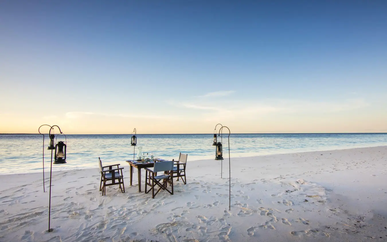 Beach dinner setup with table and chairs at sunset, Mnemba Island, Zanzibar & Pemba, Tanzania