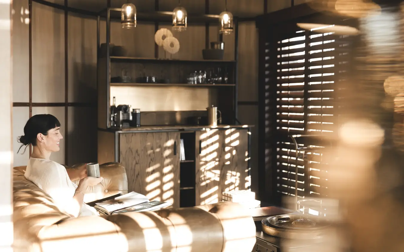 Woman relaxing in luxury lodge suite with geometric sunlight patterns, Mombo Camp, The Okavango Delta, Botswana