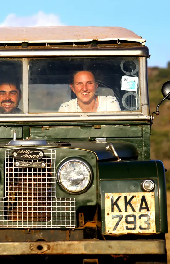 Classic Land Rover safari vehicle with guests on open grassland drive, Moon’s Camp, Laikipia Highlands, Kenya