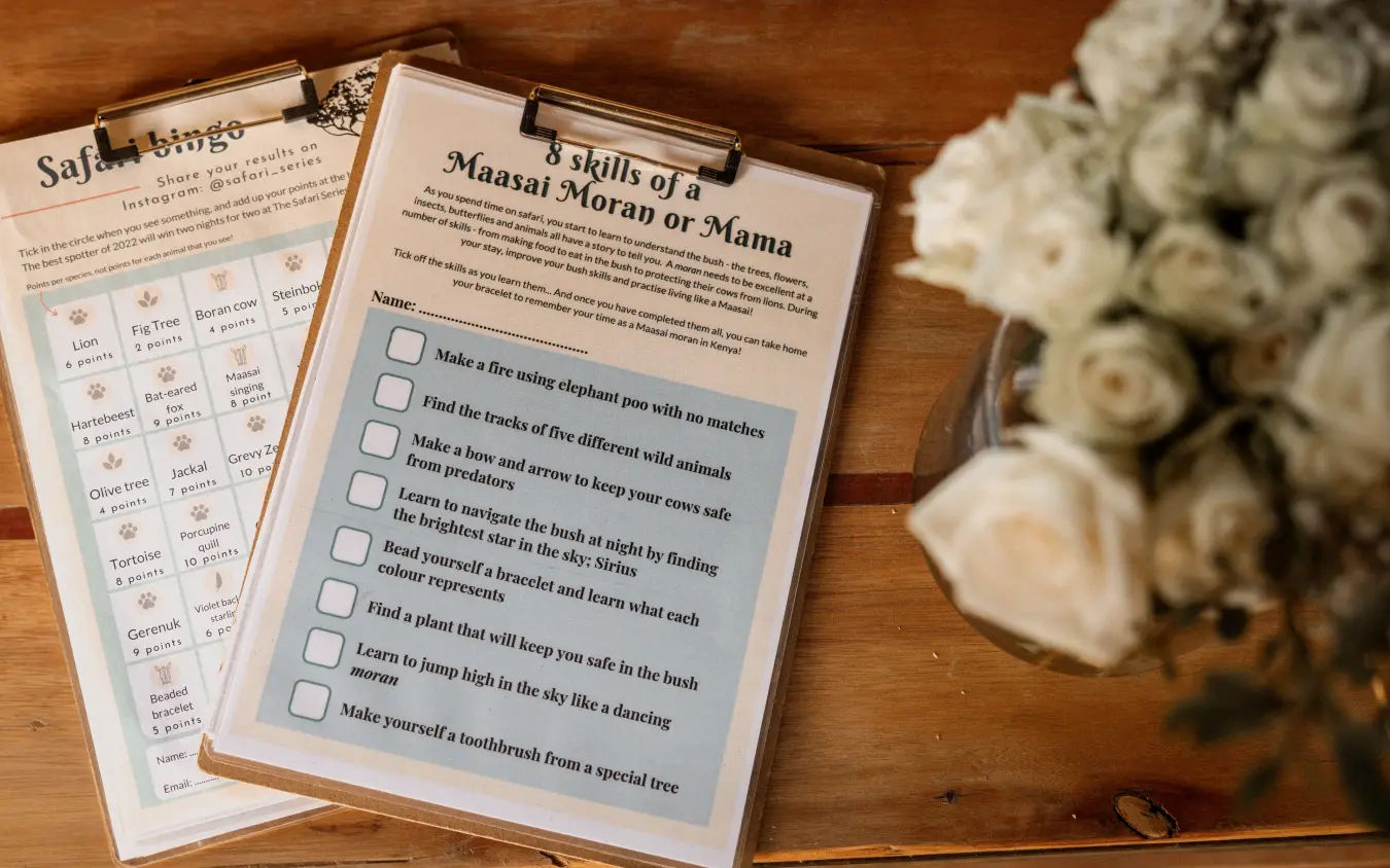 Activity worksheets and safari bingo card on wooden table with flowers, Moon’s Camp, Laikipia Highlands, Kenya