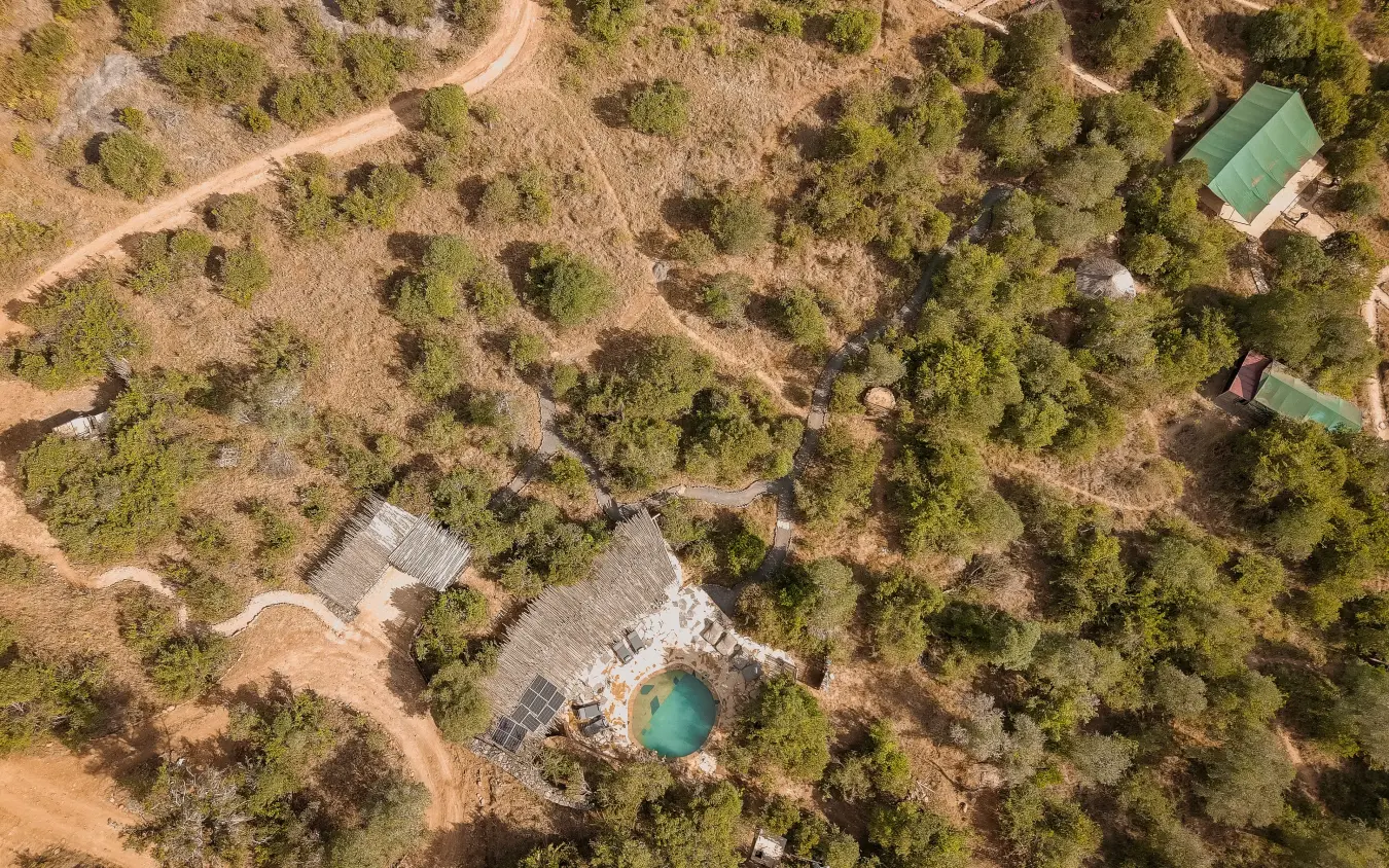 Aerial view of luxury lodge with turquoise pool nestled among forest trees, Moon’s Camp, Laikipia Highlands, Kenya