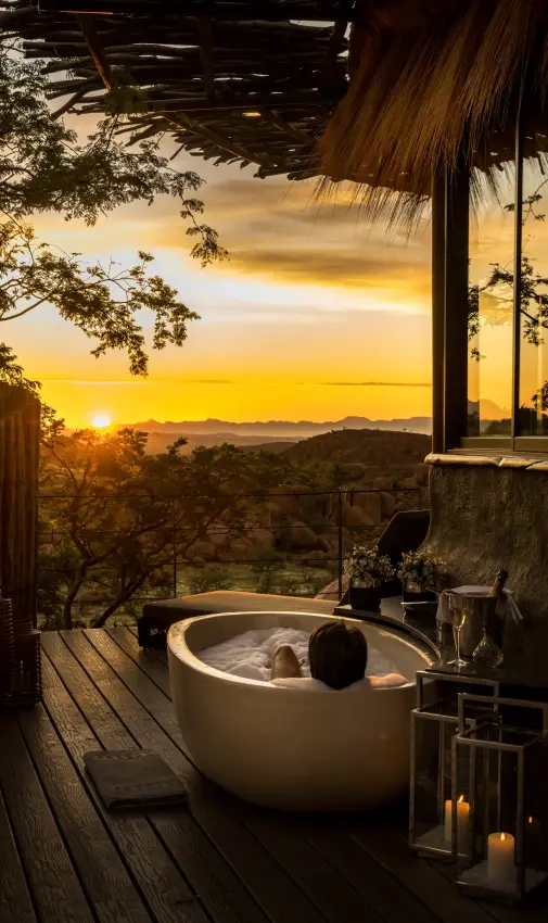 Outdoor soaking tub overlooking forested valley at sunset, Mowani Mountain Camp, Damaraland, Namibia