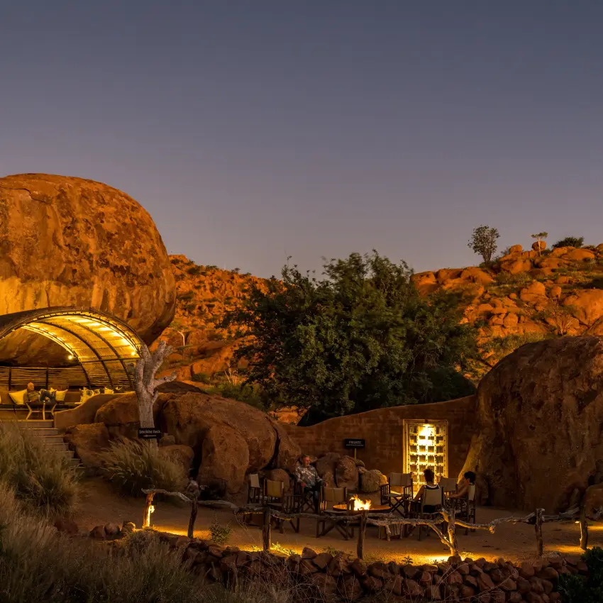 Luxury lodge built into giant boulders illuminated at dusk, Mowani Mountain Camp, Damaraland, Namibia