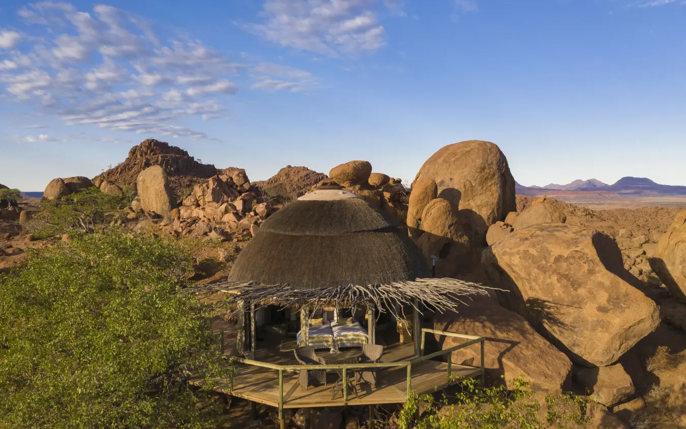 Luxury thatched-roof lodge nestled among giant boulders in arid landscape, Mowani Mountain Camp, Damaraland, Namibia