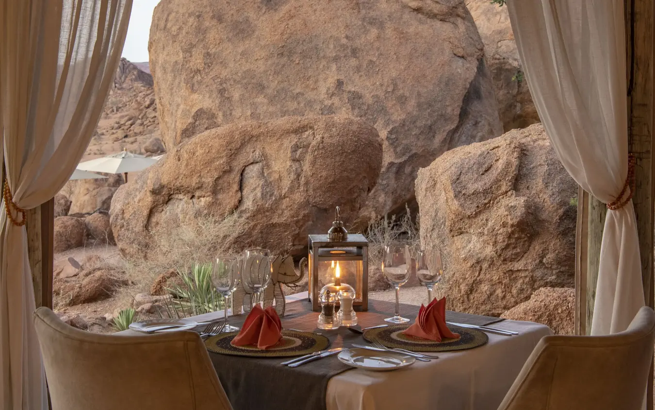 Intimate dinner table set against dramatic boulder rock formations, Mowani Mountain Camp, Damaraland, Namibia