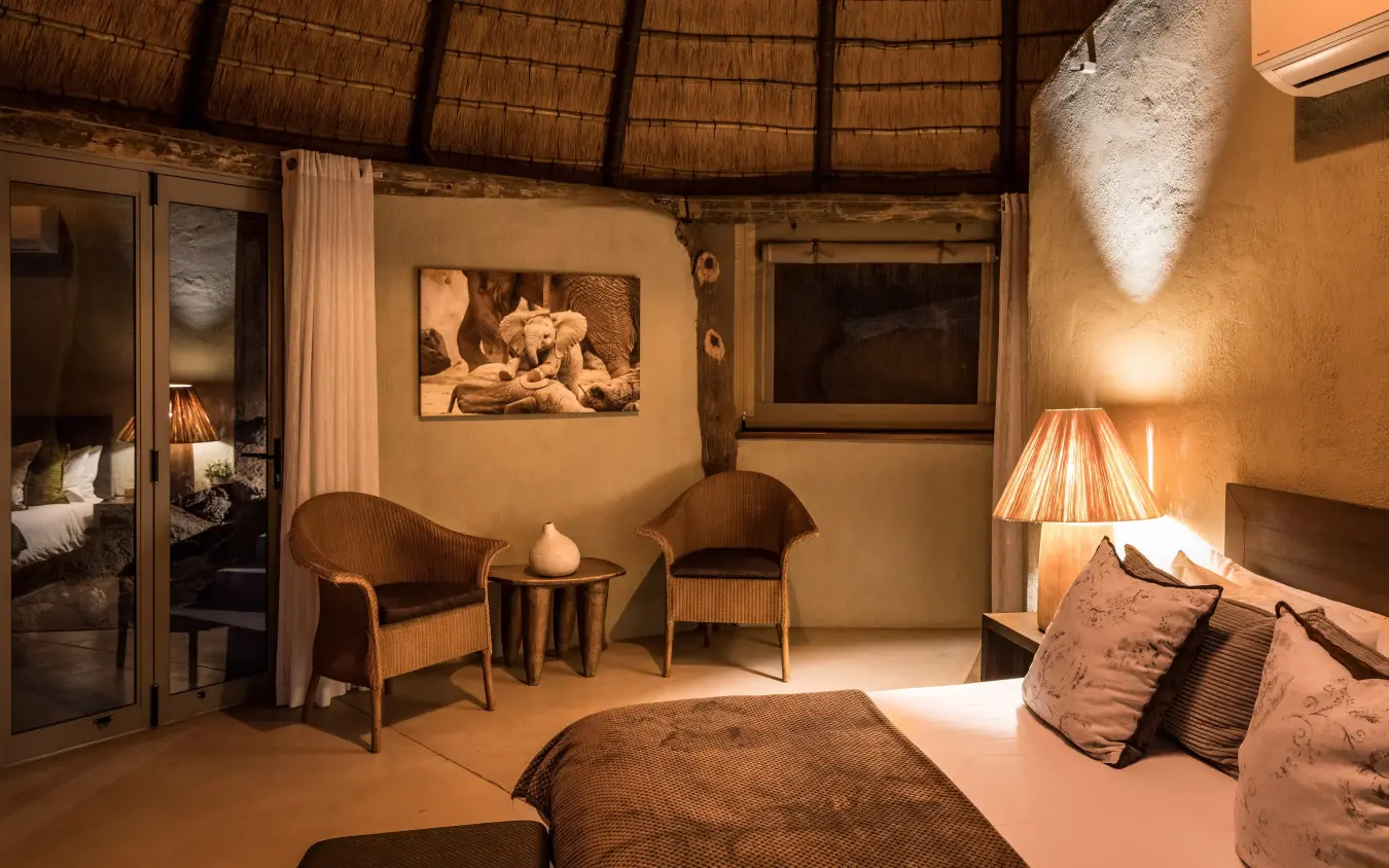 Luxury safari lodge bedroom with thatched roof and wildlife artwork, Mowani Mountain Camp, Damaraland, Namibia