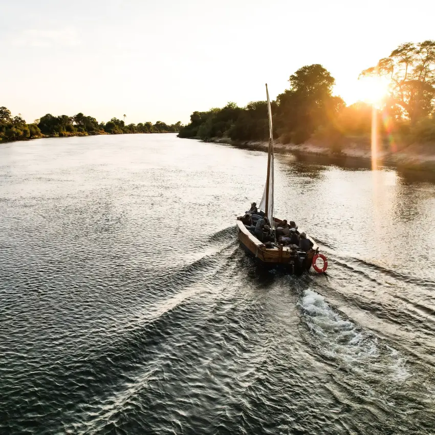 Sailboat moving across wide river at sunrise, Victoria Falls, Zimbabwe