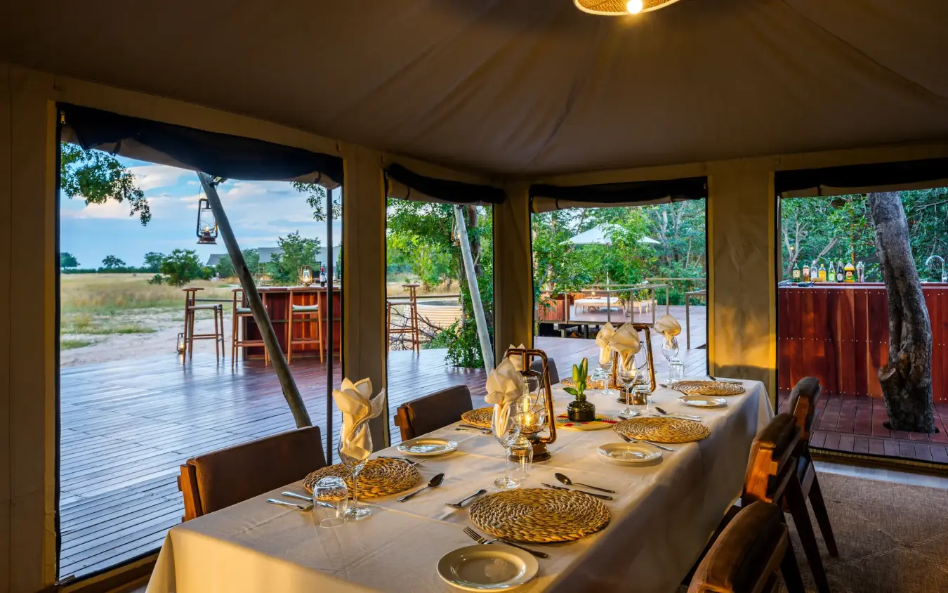 Dining pavilion with table set for dinner overlooking savanna landscape, Muddy Teak, Hwange National Park, Zimbabwe