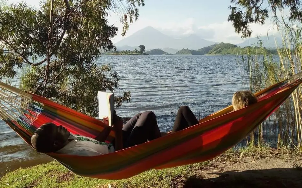 Guest relaxing in red hammock overlooking volcanic lake, Mutanda Lake Resort, Lake Mutanda, Uganda