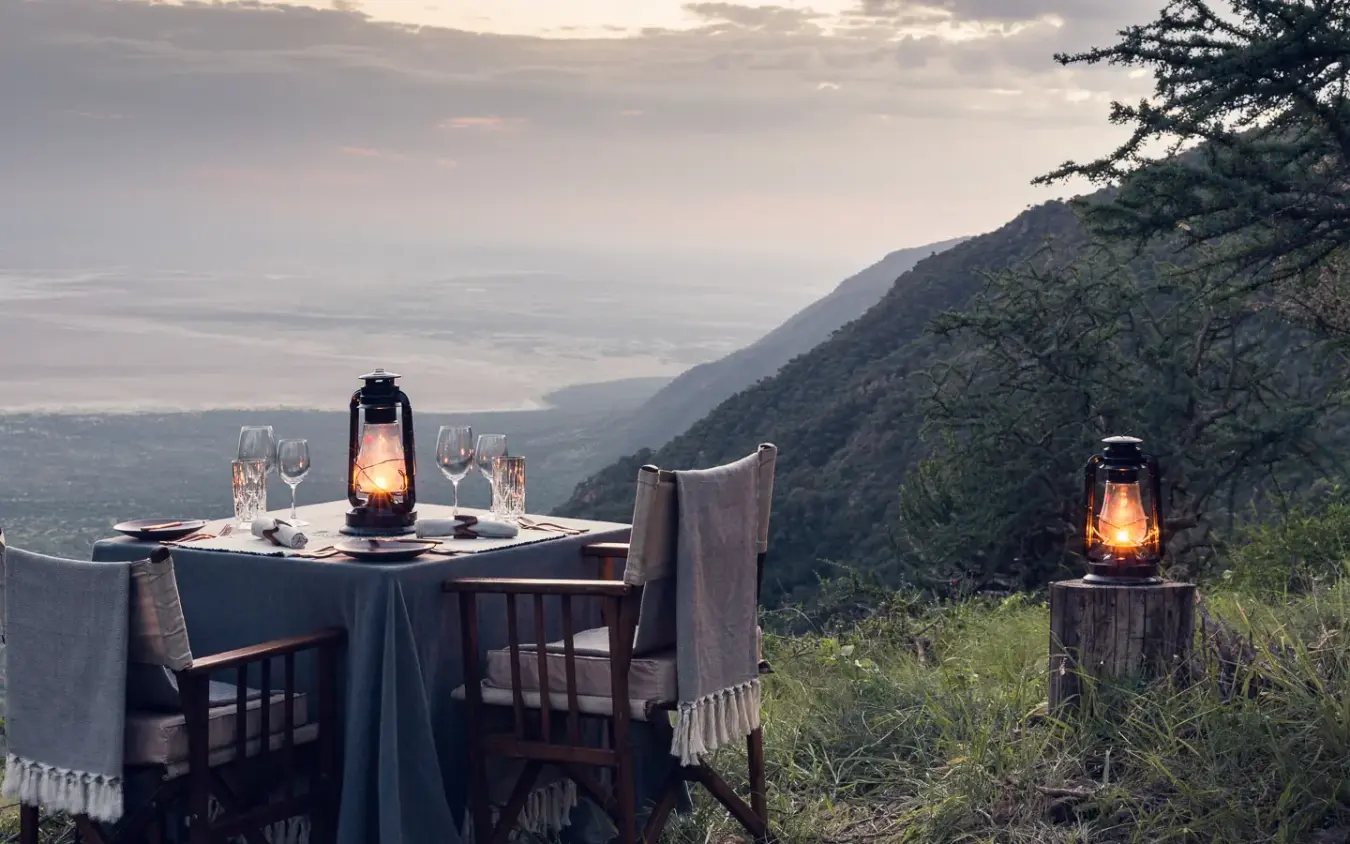 Intimate dining table set on mountain overlook at dusk, Mwiba Lodge, Serengeti National Park, Tanzania