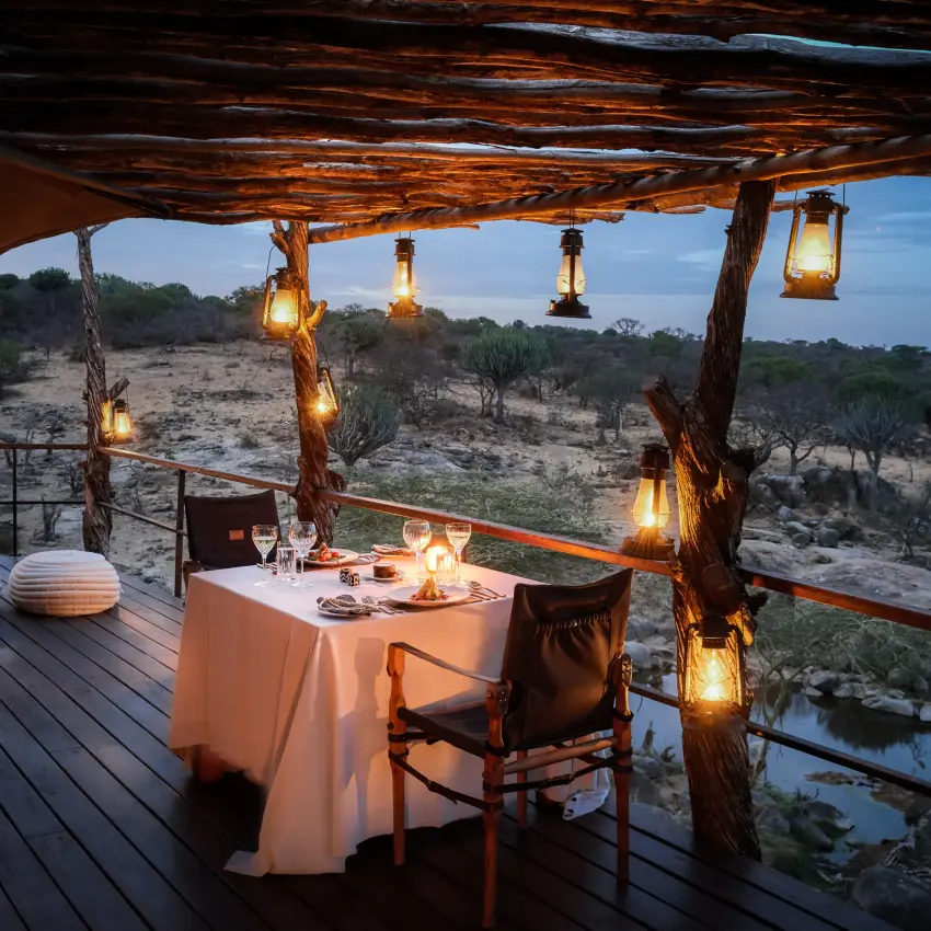 Candlelit outdoor dining deck overlooking savanna at dusk, Mwiba Lodge, Serengeti National Park, Tanzania