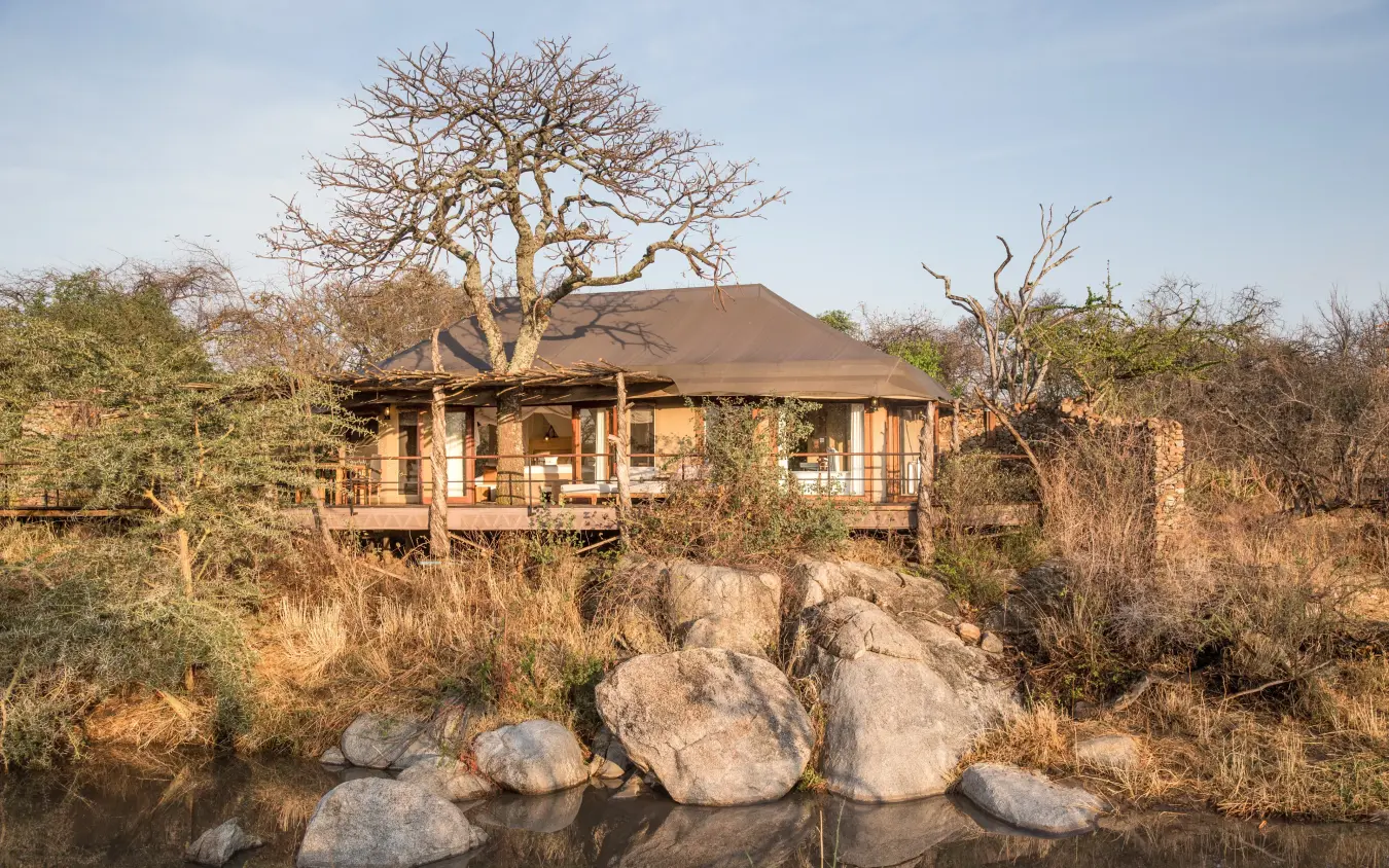 Elevated lodge structure built over waterhole with boulders, Mwiba Lodge, Serengeti National Park, Tanzania