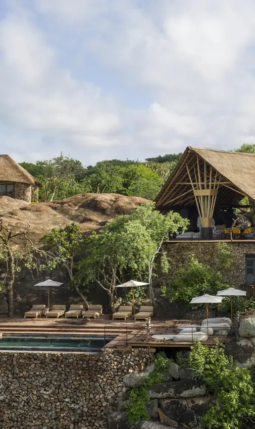 Safari lodge buildings with thatched roofs nestled among trees, Mwiba Lodge, Serengeti National Park, Tanzania