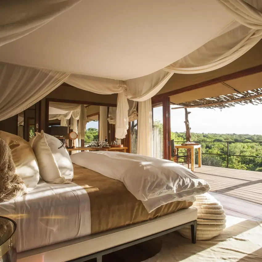 Bedroom with canopy bed overlooking savanna landscape, Mwiba Lodge, Serengeti National Park, Tanzania