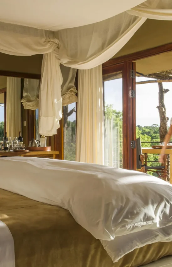 Bedroom with canopy bed overlooking savanna landscape, Mwiba Lodge, Serengeti National Park, Tanzania