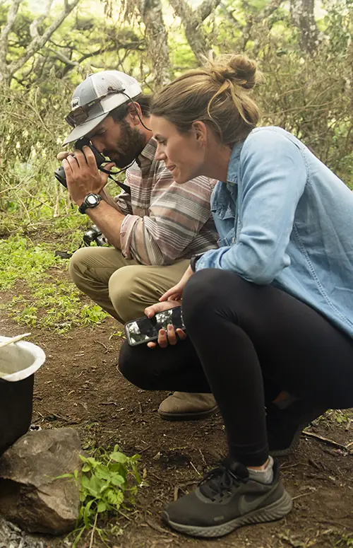 Guests observe traditional cooking preparation in forest setting, Mysigio Camp, Ngorongoro Crater, Tanzania