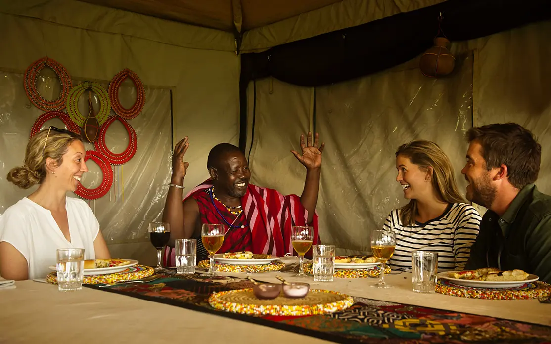 Guests dining together under canvas tent at night, Mysigio Camp, Ngorongoro Crater, Tanzania