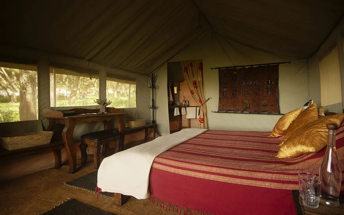Luxury safari tent bedroom with red bedding and natural light, Mysigio Camp, Ngorongoro Crater, Tanzania