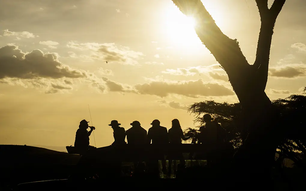 Guests silhouetted against golden sunset sky during activity, Mysigio Camp, Ngorongoro Crater, Tanzania