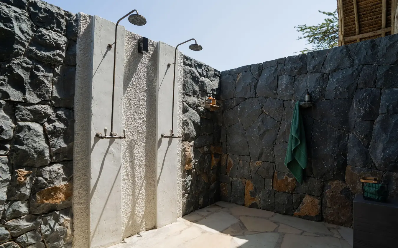 Outdoor shower enclosure with stone walls and rainfall heads, Naboisho Camp, Maasai Mara, Kenya