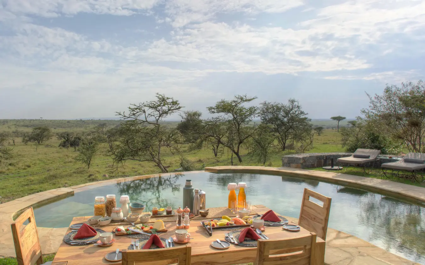 Dining table set overlooking savanna landscape and pool, Naboisho Camp, Maasai Mara, Kenya