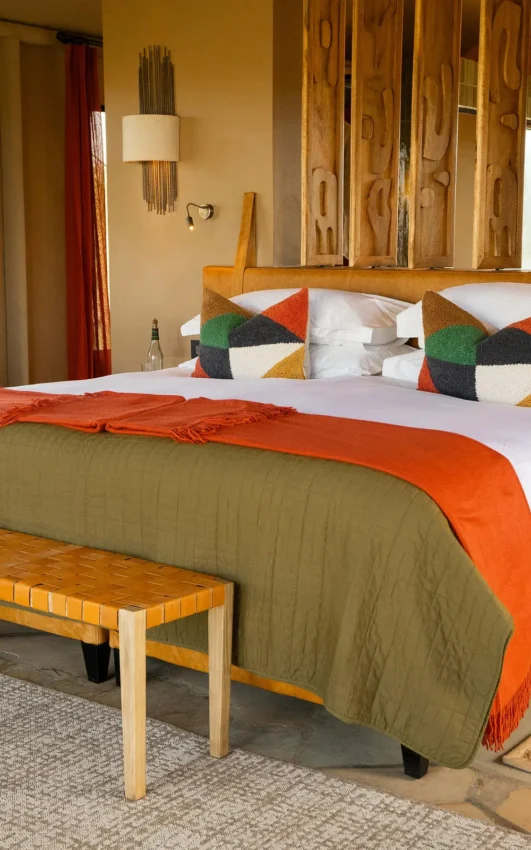 Bedroom with wooden bed frame and geometric pillows, Naboisho Camp, Maasai Mara, Kenya