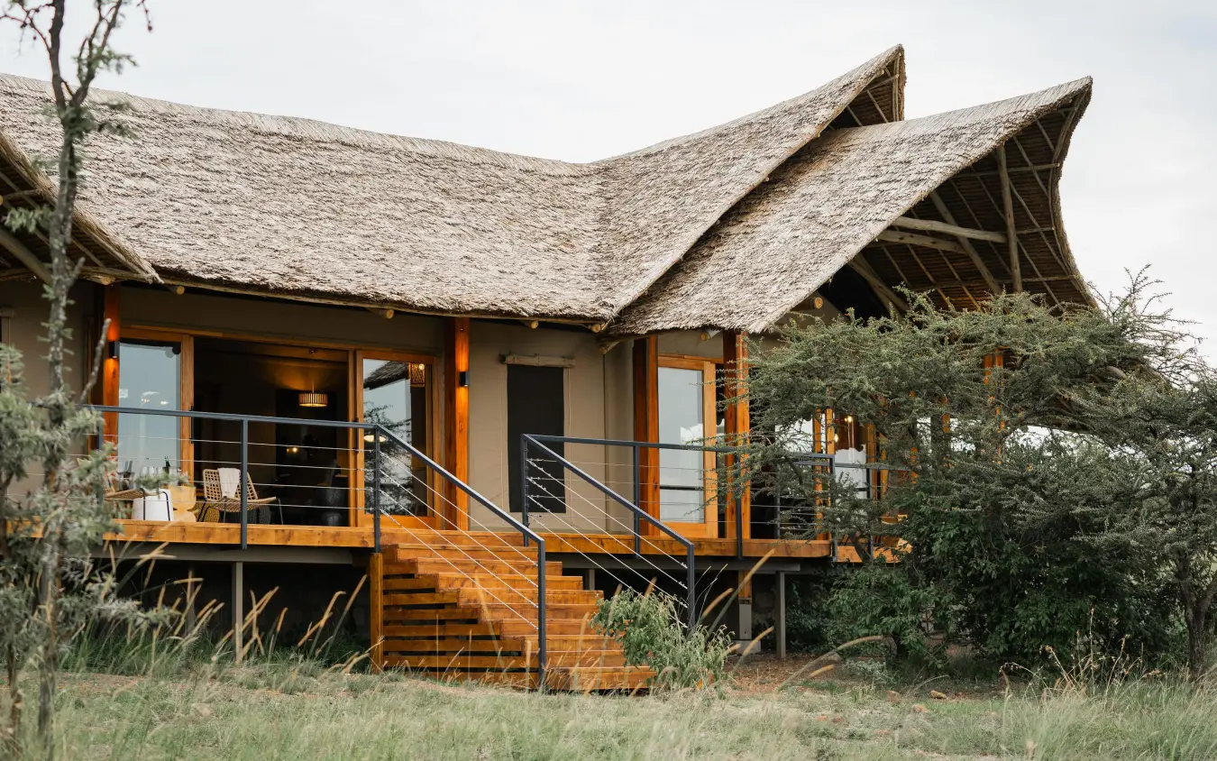 Thatched-roof safari lodge with wooden deck and railings, Naboisho Camp, Maasai Mara, Kenya