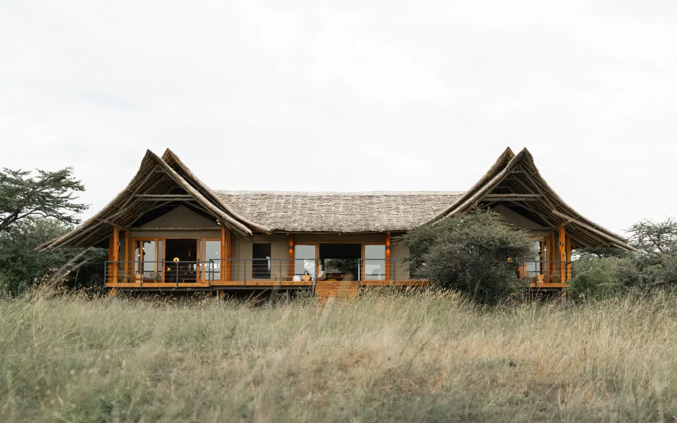 Low-profile safari lodge with peaked roofs in grassland, Naboisho Camp, Maasai Mara, Kenya