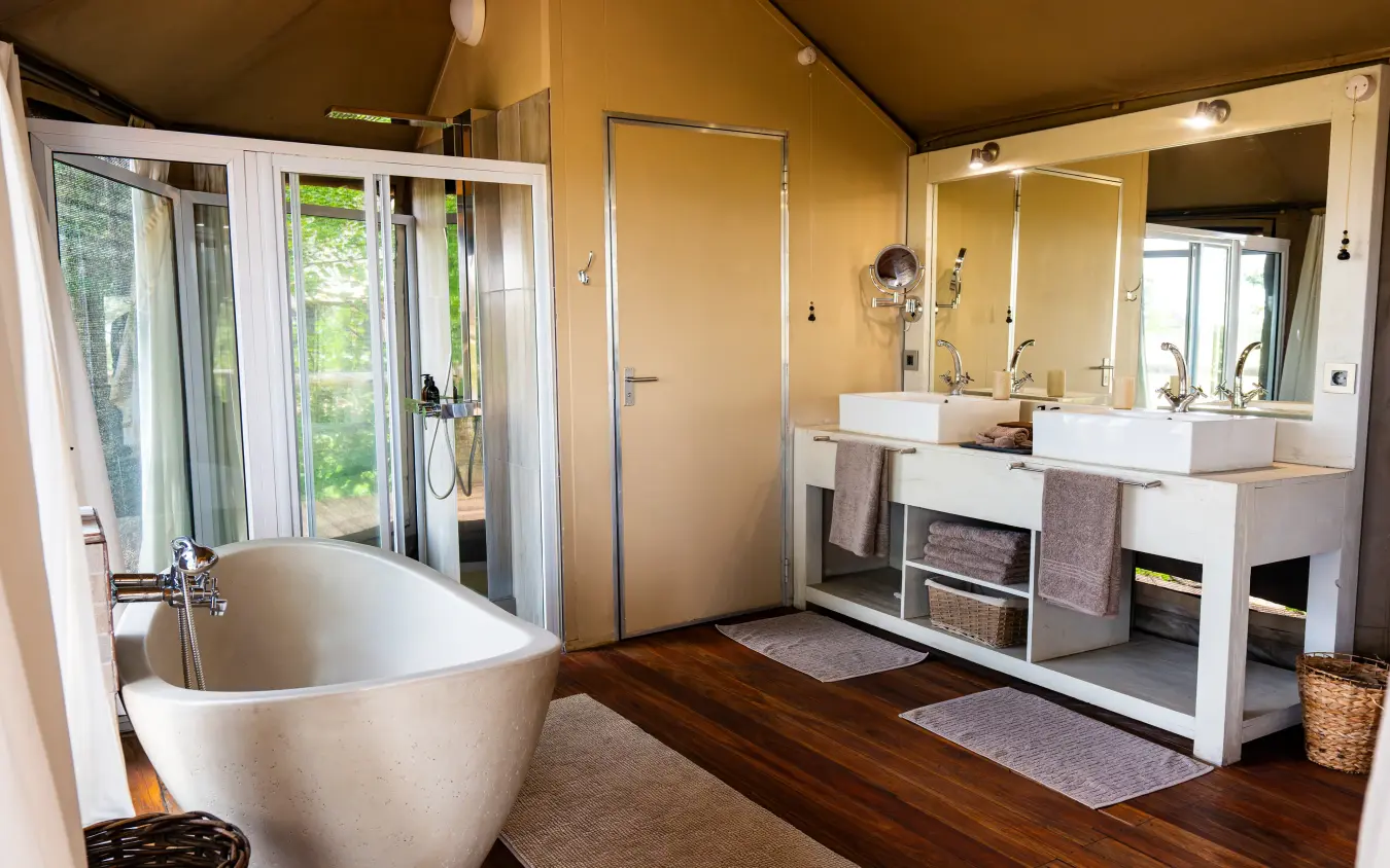 Luxury bathroom with freestanding tub and dual vanities overlooking natural landscape, Nambwa Tented Lodge, Zambezi Region, Namibia