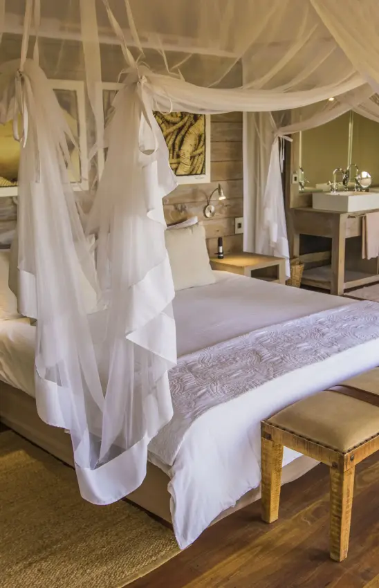 Four-poster canopy bed with white drapes in luxury bedroom suite, Nambwa Tented Lodge, Zambezi Region, Namibia