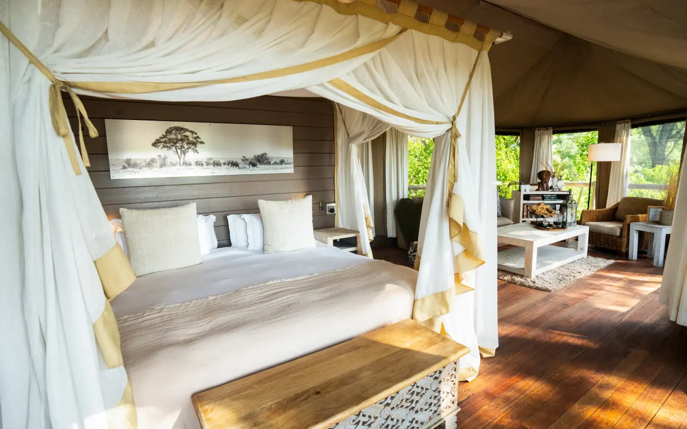 Luxury safari bedroom with draped four-poster bed and savanna views, Nambwa Tented Lodge, Zambezi Region, Namibia