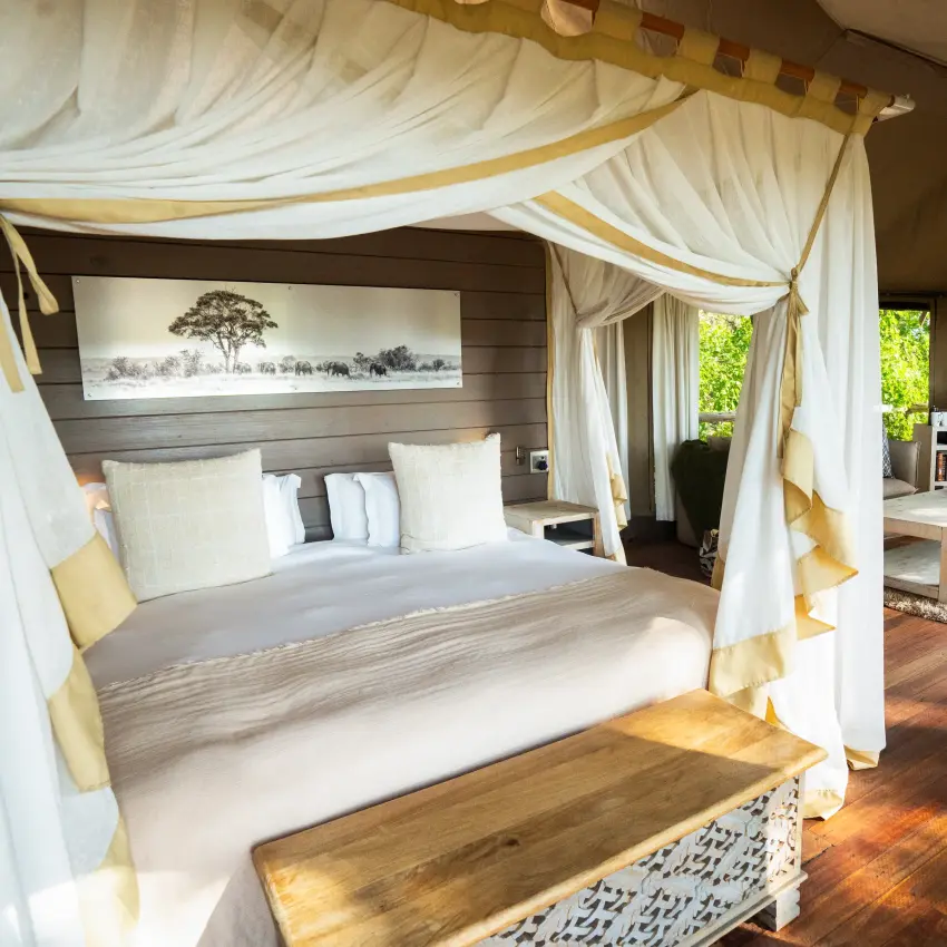 Luxury safari bedroom with draped four-poster bed and savanna views, Nambwa Tented Lodge, Zambezi Region, Namibia