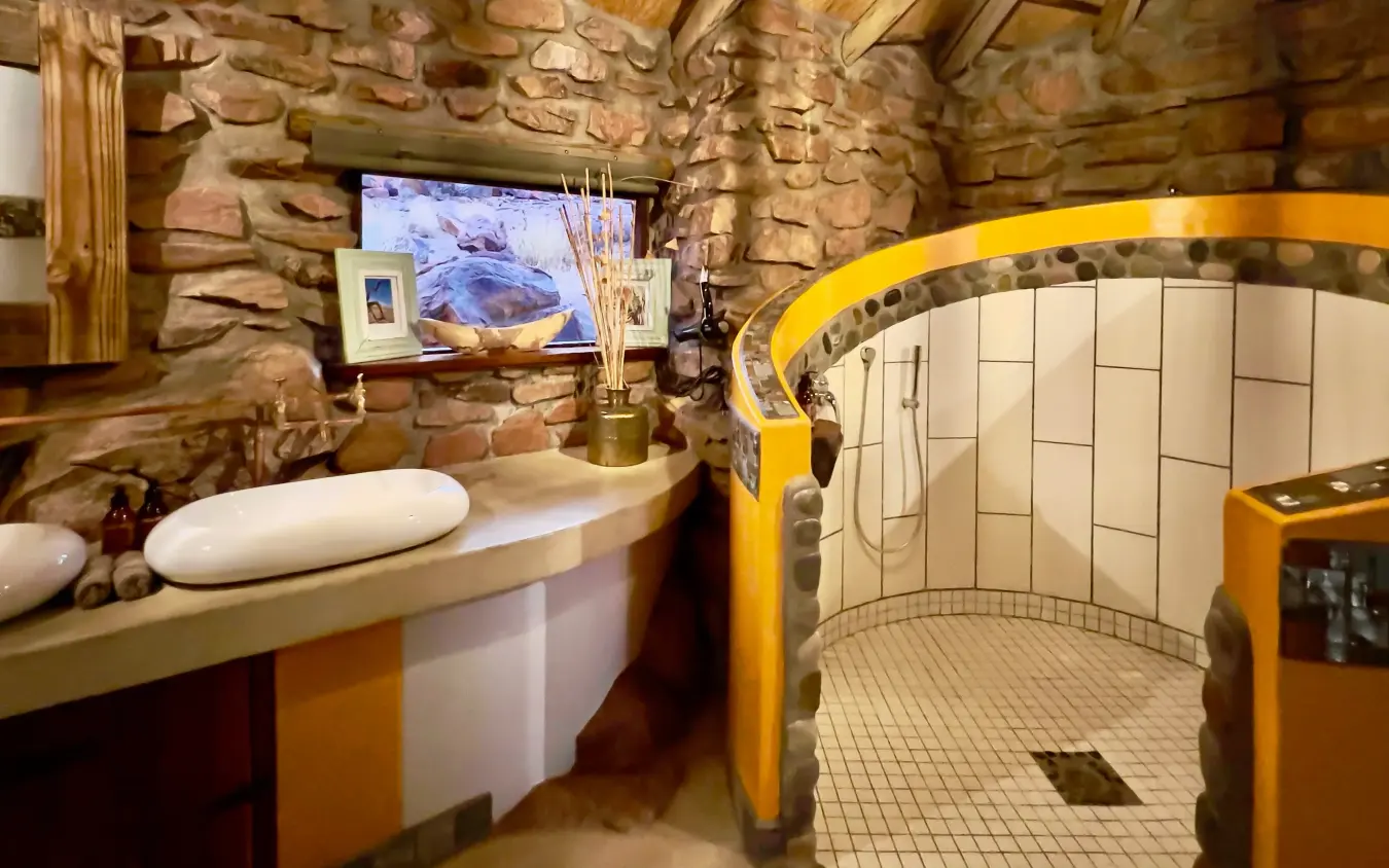 Luxury bathroom with curved shower enclosure and stone walls, Namib Outpost, Sossusvlei, Namibia
