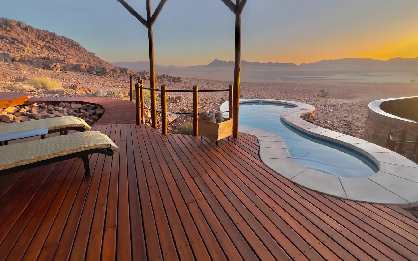Wooden deck with loungers overlooking desert valley at sunset, Namib Outpost, Sossusvlei, Namibia