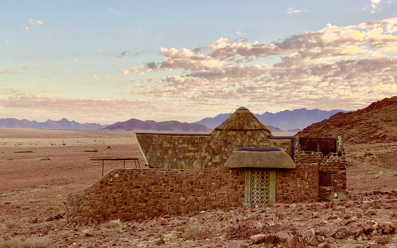Abandoned stone structure with metal roof in desert landscape at sunset, Namib Outpost, Sossusvlei, Namibia