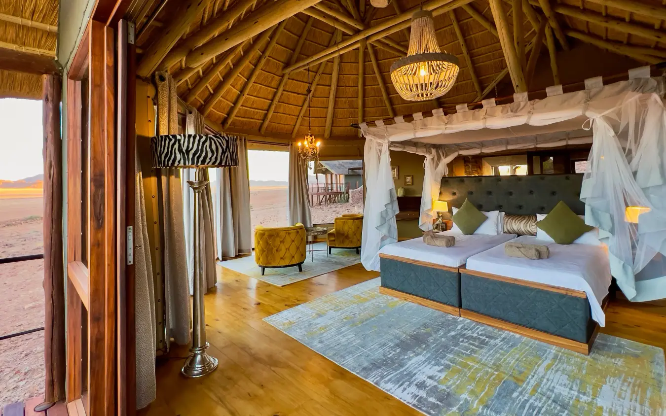 Luxury safari suite with canopy bed and savanna views from wooden pavilion, Namib Outpost, Sossusvlei, Namibia