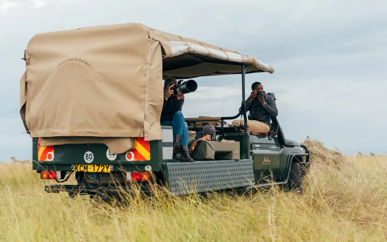 Safari vehicle with guests photographing wildlife in grassland, Namiri Plains, Serengeti National Park, Tanzania