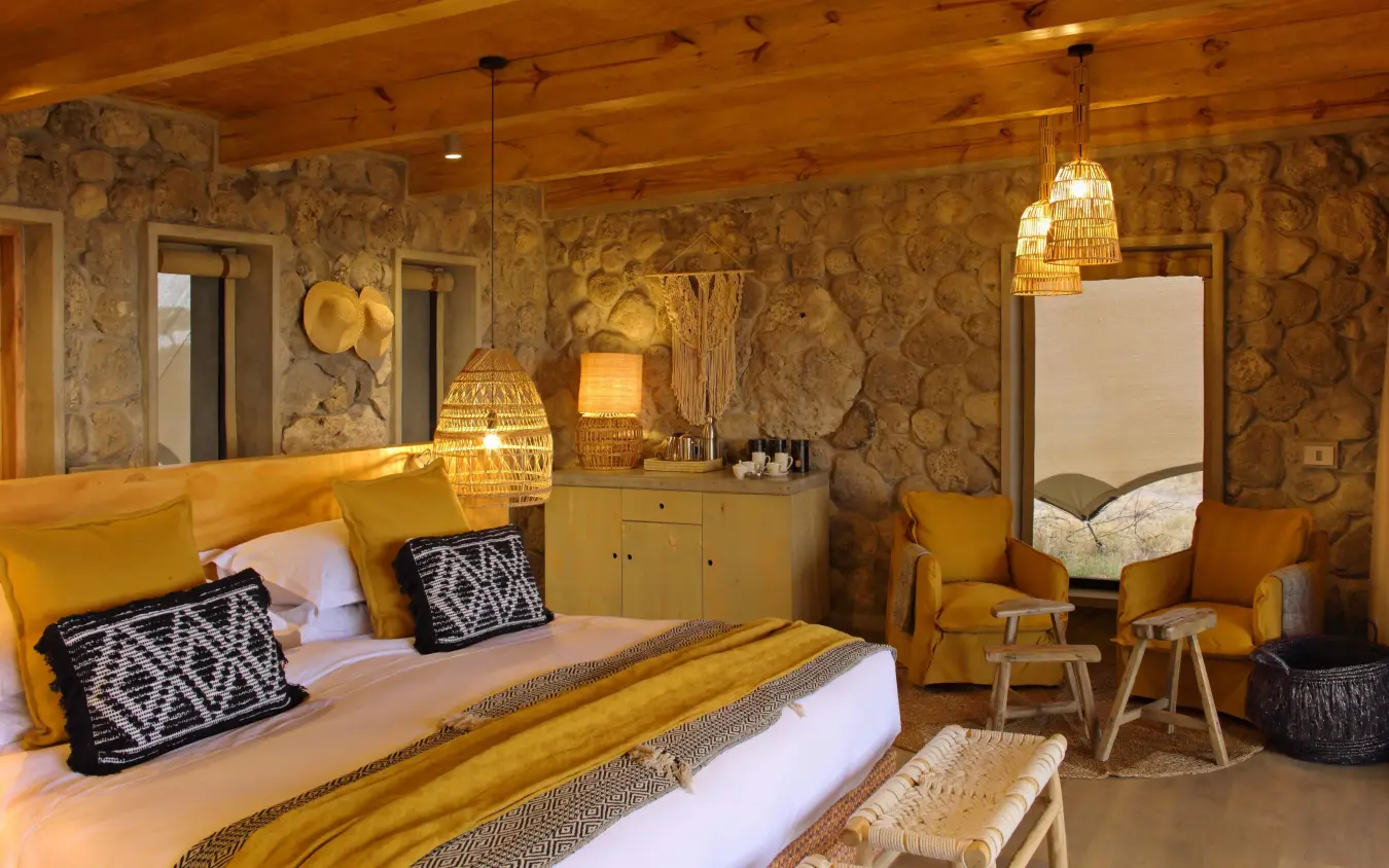 Luxury bedroom with gold accents and patterned wallpaper, Namiri Plains, Serengeti National Park, Tanzania
