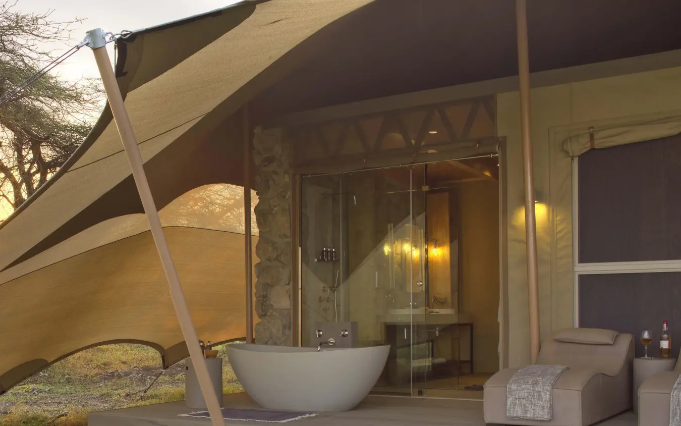 Outdoor bedroom with soaking tub under shade sail, Namiri Plains, Serengeti National Park, Tanzania