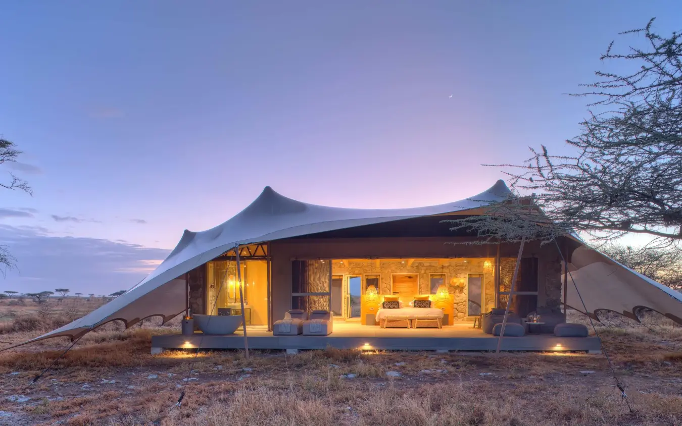 Illuminated safari tent in African savanna at dusk, Namiri Plains, Serengeti National Park, Tanzania