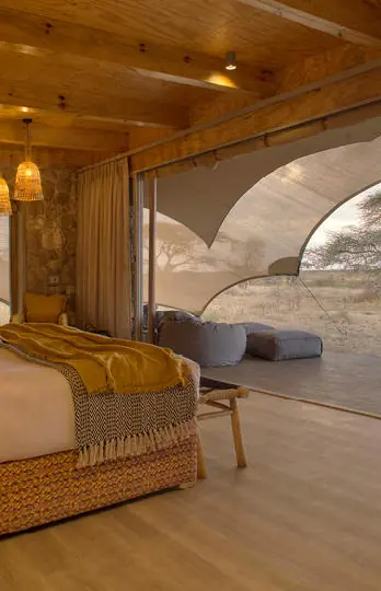Luxury bedroom with curved glass walls overlooking savanna, Namiri Plains, Serengeti National Park, Tanzania